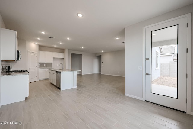 kitchen featuring a kitchen island with sink, light hardwood / wood-style flooring, stainless steel appliances, sink, and white cabinetry