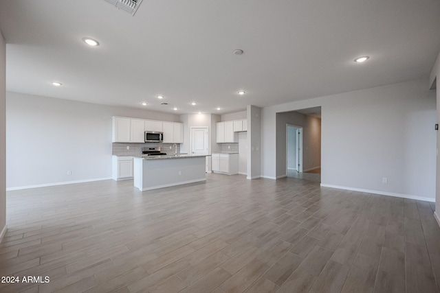 unfurnished living room with light hardwood / wood-style flooring and sink