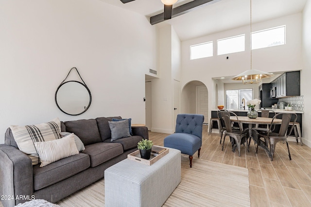 living area with visible vents, wood tiled floor, a chandelier, beamed ceiling, and arched walkways