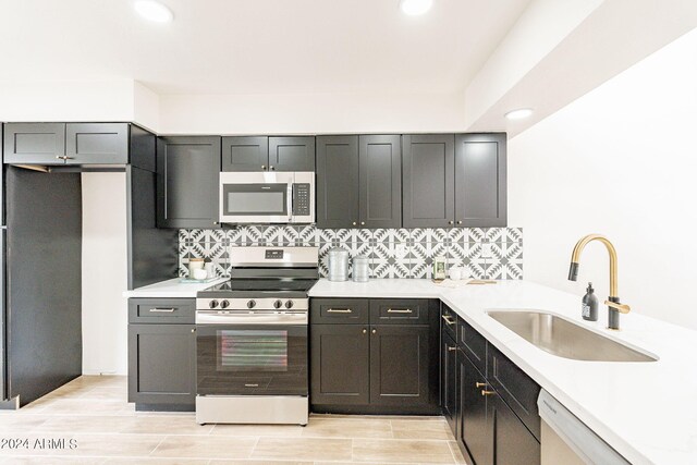 kitchen with backsplash, light countertops, recessed lighting, stainless steel appliances, and a sink