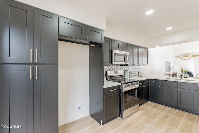 kitchen featuring wood tiled floor, a sink, light countertops, appliances with stainless steel finishes, and backsplash