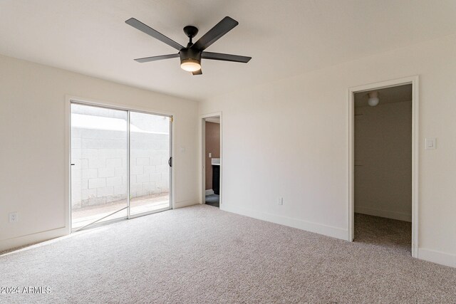 unfurnished bedroom with a walk in closet, a ceiling fan, carpet floors, baseboards, and access to exterior