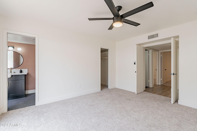 unfurnished bedroom with visible vents, connected bathroom, baseboards, ceiling fan, and light carpet