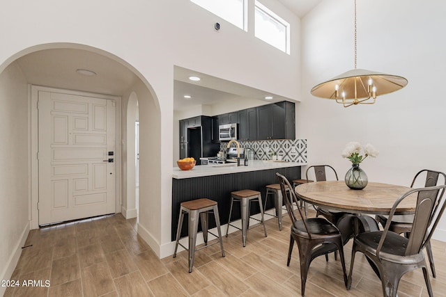 dining room featuring arched walkways, baseboards, a chandelier, and wood finish floors