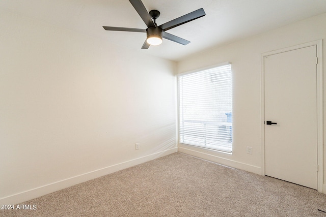 unfurnished room with a ceiling fan, baseboards, and light carpet