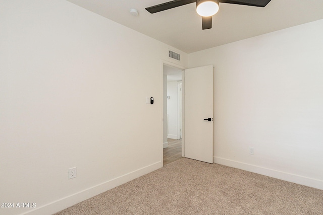 unfurnished room with light carpet, visible vents, a ceiling fan, and baseboards