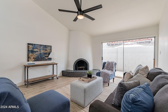 living area with baseboards, lofted ceiling, a fireplace, ceiling fan, and light wood-style floors