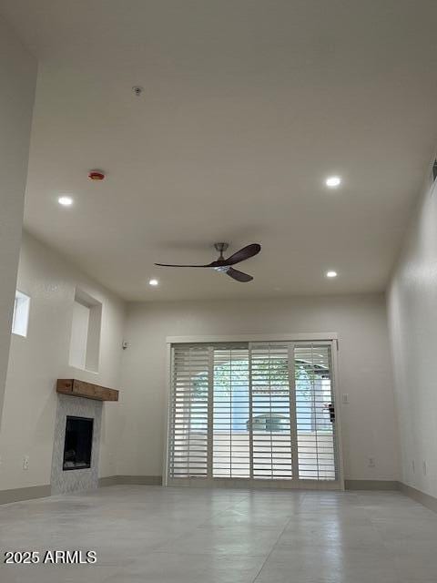 unfurnished living room with ceiling fan, a premium fireplace, baseboards, and recessed lighting