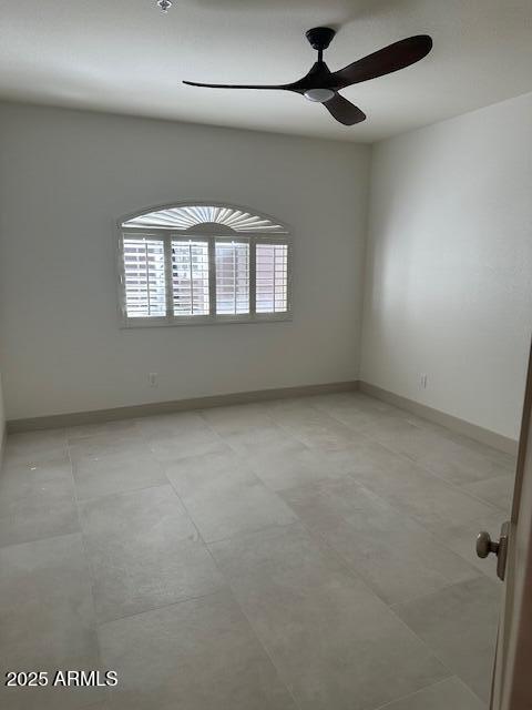 spare room featuring baseboards, ceiling fan, and a healthy amount of sunlight