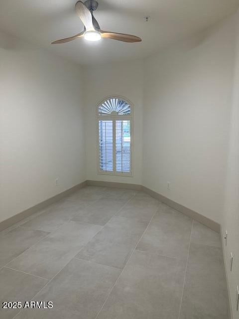 spare room featuring light tile patterned floors, baseboards, and a ceiling fan