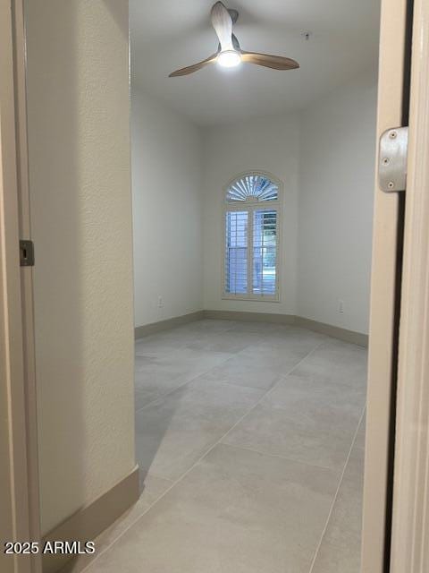 spare room with ceiling fan and baseboards