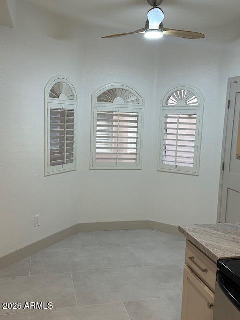 unfurnished room with ceiling fan, baseboards, and light tile patterned floors