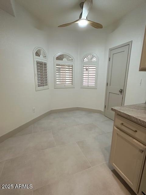 unfurnished dining area featuring a ceiling fan and baseboards