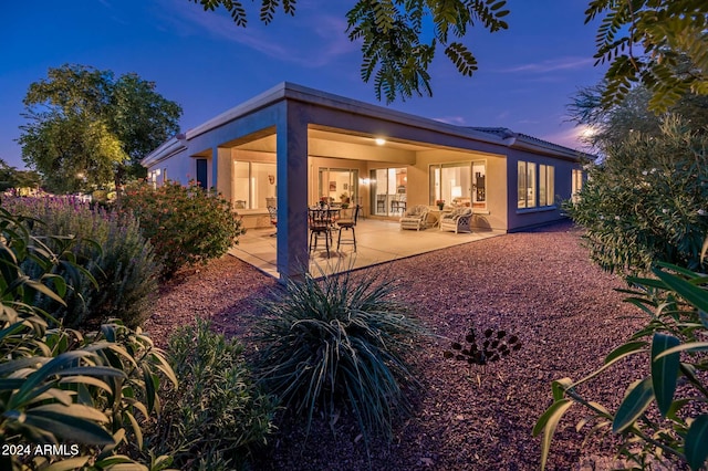 back house at dusk featuring a patio