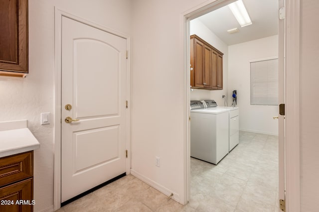 clothes washing area with cabinets and independent washer and dryer