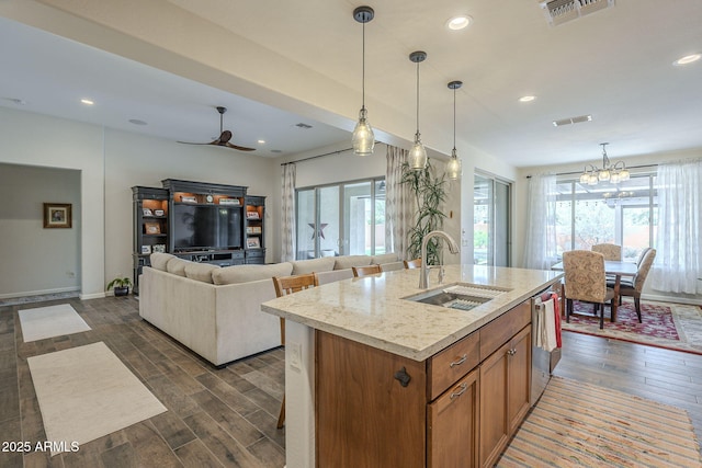 kitchen with a sink, visible vents, a healthy amount of sunlight, brown cabinetry, and dark wood finished floors