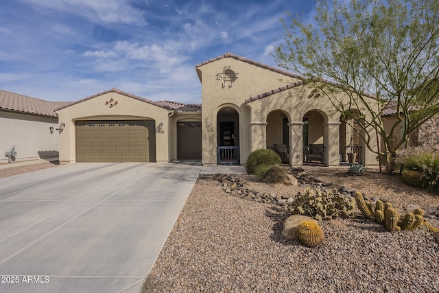 mediterranean / spanish-style home with a garage, concrete driveway, a tiled roof, and stucco siding