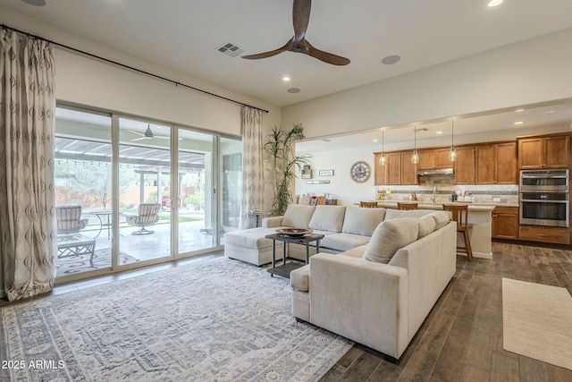 living room with dark wood-style floors, visible vents, and a ceiling fan