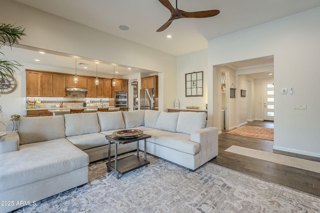 living area featuring light wood finished floors, ceiling fan, baseboards, and recessed lighting