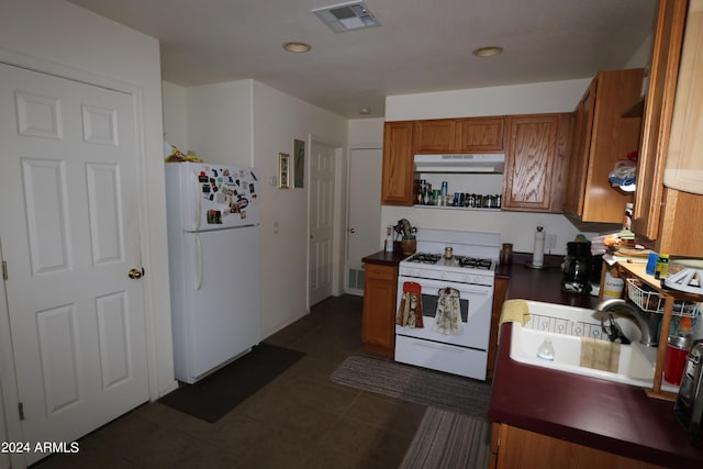 kitchen with dark tile patterned flooring, sink, and white appliances