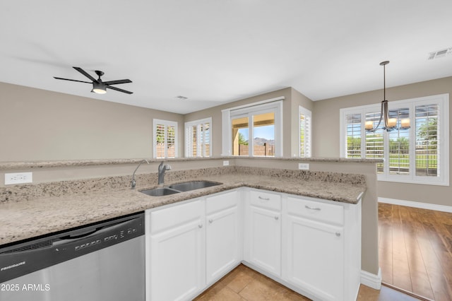kitchen featuring dishwasher, a sink, baseboards, light stone counters, and a chandelier