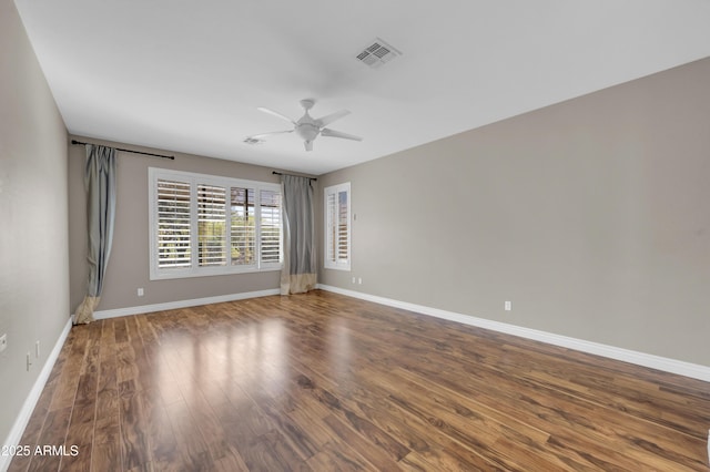 empty room featuring ceiling fan, baseboards, and wood finished floors