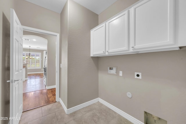 laundry room featuring electric dryer hookup, hookup for a washing machine, cabinet space, light tile patterned floors, and baseboards
