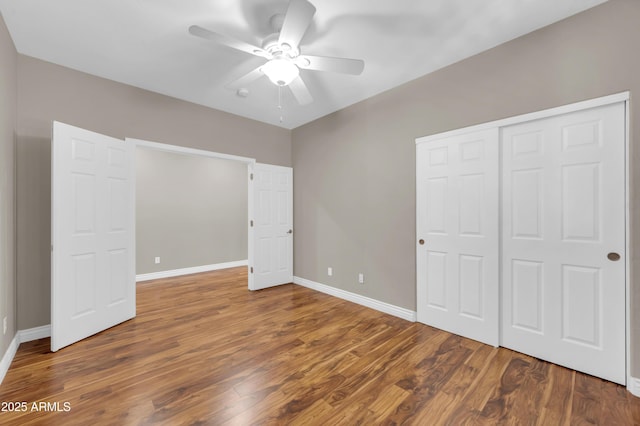 unfurnished bedroom with baseboards, wood finished floors, and a closet