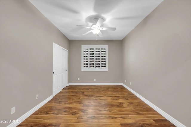 empty room with ceiling fan, wood finished floors, and baseboards