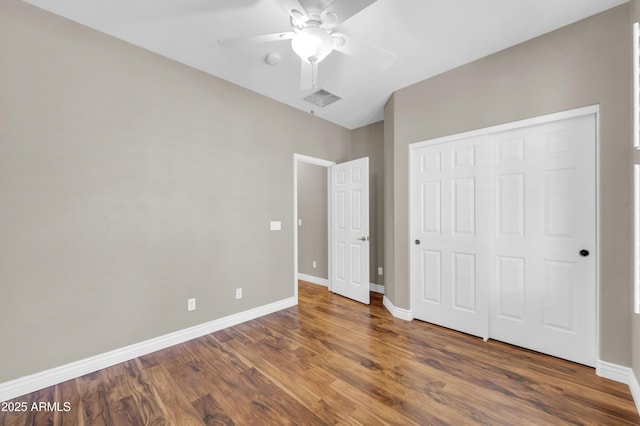 unfurnished bedroom with wood finished floors, baseboards, a closet, and ceiling fan