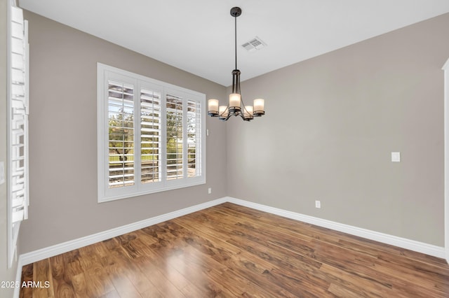 spare room featuring baseboards, a chandelier, and wood finished floors