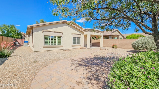 rear view of property featuring stucco siding, a fenced backyard, and a patio