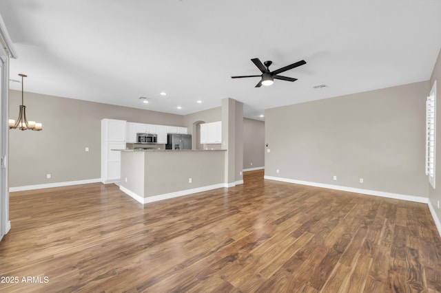 unfurnished living room featuring a ceiling fan, a chandelier, baseboards, and recessed lighting