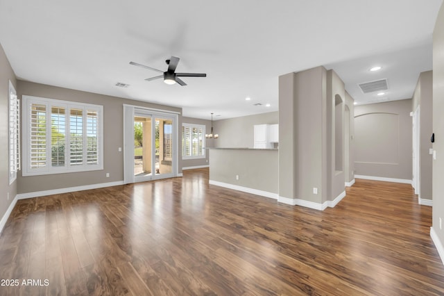 unfurnished living room featuring dark wood-style floors, baseboards, a ceiling fan, recessed lighting, and a chandelier