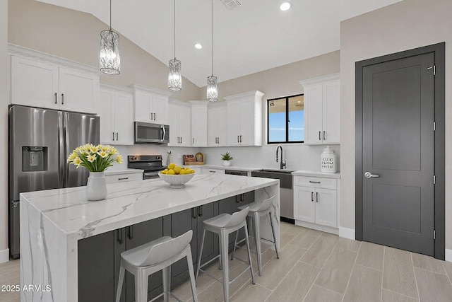 kitchen featuring white cabinets, lofted ceiling, stainless steel appliances, and a kitchen breakfast bar