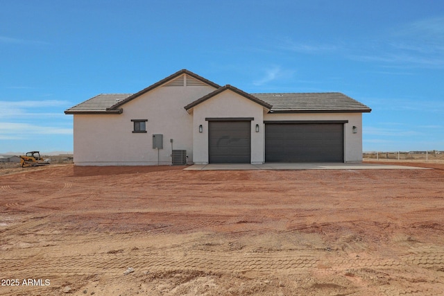 view of front of property with an attached garage, central AC, driveway, a tiled roof, and stucco siding