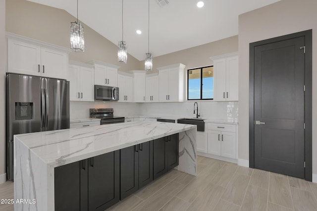 kitchen with appliances with stainless steel finishes, white cabinets, a sink, and a center island