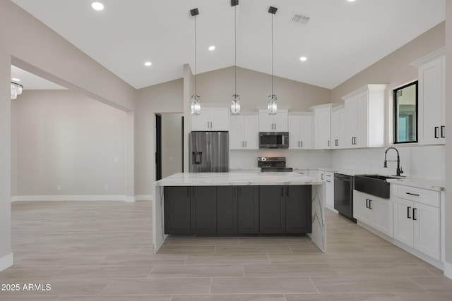 kitchen featuring visible vents, a center island, stainless steel appliances, white cabinetry, and a sink