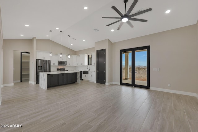 kitchen with stainless steel appliances, a kitchen island, white cabinetry, open floor plan, and light countertops