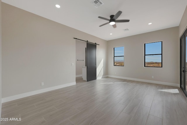 unfurnished bedroom featuring a barn door, visible vents, baseboards, and recessed lighting