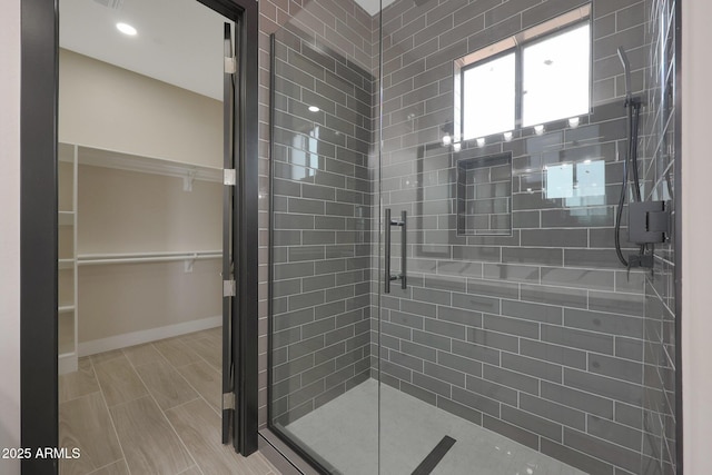 full bath with a shower stall, a spacious closet, and baseboards