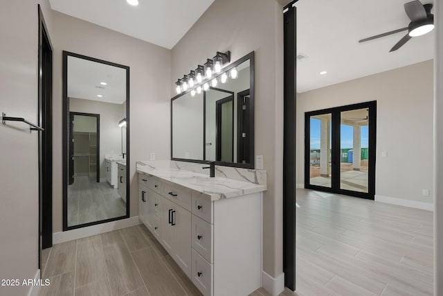 bathroom with wood finish floors, vanity, baseboards, and recessed lighting