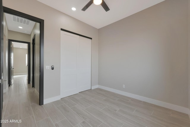 unfurnished bedroom with a ceiling fan, wood tiled floor, visible vents, and baseboards