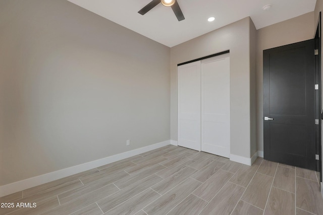 unfurnished bedroom featuring wood tiled floor, a closet, ceiling fan, and baseboards