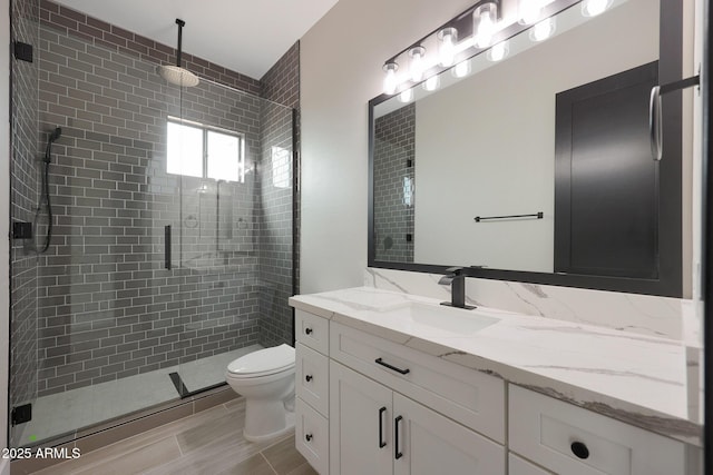 bathroom with a shower stall, toilet, and vanity