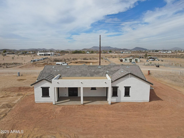 rear view of house with stucco siding, a patio, and a mountain view