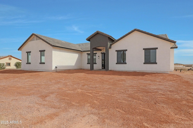 rear view of property with a tile roof and stucco siding