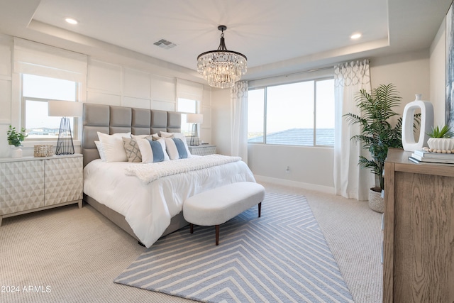 carpeted bedroom with a tray ceiling and a notable chandelier