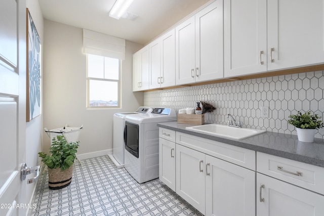 laundry room featuring washing machine and clothes dryer, sink, and cabinets