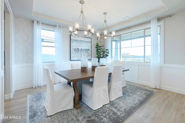 dining room with a chandelier, light hardwood / wood-style floors, and a tray ceiling